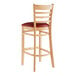 A Lancaster Table & Seating wooden bar stool with a burgundy vinyl seat.