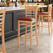 A Lancaster Table & Seating wooden bar stool with a detached red vinyl seat.