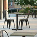 Lancaster Table & Seating Excalibur outdoor table with table and chairs on a patio.