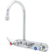 A T&S chrome wall mount faucet with a swivel gooseneck spout and two handles, one red.