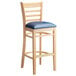 A Lancaster Table & Seating wooden bar stool with a navy blue cushion.