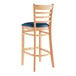 A Lancaster Table & Seating wooden bar stool with a navy blue cushion.