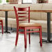 A Lancaster Table & Seating mahogany wood chair with a light brown vinyl seat in a restaurant