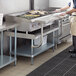 A man standing in a kitchen using a Regency stainless steel equipment stand with a grill.