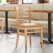 A Lancaster Table & Seating wooden restaurant chair with a light brown vinyl seat.