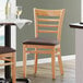 A Lancaster Table & Seating wooden chair with a dark brown vinyl seat.