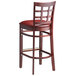 A Lancaster Table & Seating mahogany wood bar stool with a burgundy vinyl seat.