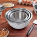 A stack of OXO stainless steel mixing bowls on a table.