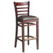 A Lancaster Table & Seating mahogany wood bar stool with a dark brown vinyl seat and ladder back.