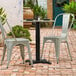 A black table base on a brick patio with two chairs.