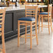 A Lancaster Table & Seating wooden bar stool with a navy vinyl seat.