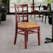 A Lancaster Table & Seating mahogany wood chair with a light brown vinyl seat at a table in a restaurant