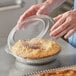 A person holding a Choice clear plastic container with pie inside.