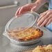 A person holding a Choice clear plastic container with a pie inside.