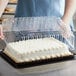 A person holding a Choice clear plastic container with a lid containing a sheet cake.