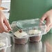 A woman holding a Choice plastic container with a cupcake inside.