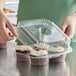 A woman holding a Choice clear plastic container with cupcakes.