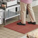 A person standing on a red Choice anti-fatigue floor mat.