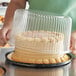 A person holding a cake in a Choice plastic cake display container.