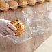 A hand holding a muffin in a Choice clear plastic container.