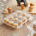 A hand putting mini muffins into a clear plastic container with 12 compartments.