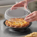 a person holding a plastic container over a pie