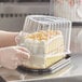 A person putting a cake into a Choice plastic container.