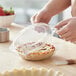 A person holding a Choice clear plastic pie container with food inside.