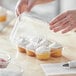 A person putting a cupcake in a Choice plastic container.