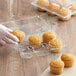 A person in gloves holding a cupcake in a Choice plastic container.