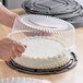 A person using a Choice plastic container with a clear dome lid to store a cake.