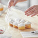 A person putting a cupcake in a Choice plastic container.