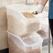 A woman using an Araven polypropylene shelf ingredient bin to pour cereal into.