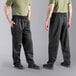 The legs and torso of a man wearing Uncommon Chef black pants and a green shirt.