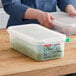 A person holding a Araven translucent plastic food pan filled with green peas.