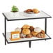 A Cal-Mil Monterey 2-tier riser holding cookies and a plant on a table.