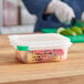 A person cutting up vegetables in an Araven translucent plastic food pan on a counter.