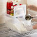 A person pouring rice into an Araven ingredient container on a wire rack in a home kitchen.