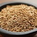 A bowl of Regal Cumin Seeds on a wooden table.