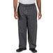 A person wearing Uncommon Chef black and white chalk stripe chef pants.