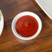 A plate of food with a white bowl of red sauce and a bowl of vegetables.