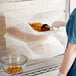 A woman in a blue shirt putting pasta in an Araven ingredient bin.