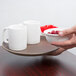 A person holding a Tavern Tan non-skid serving tray with two white mugs and a bowl of raspberries.