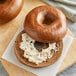 A close up of a New York style Pumpernickel bagel with cream cheese on top.