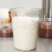 A clear Fabri-Kal deli container filled with white and brown pudding.