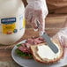 A person spreading Hellmann's Real Mayonnaise on a sandwich with a knife.