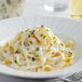 A white plate of pasta with Knorr alfredo sauce and parsley.