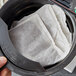 A person's finger holding a Lipton Black Iced Tea filter bag.