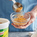 A person pouring yellow shrimp bouillon powder into a bowl.