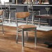 A metal chair with a clear coat finish and light brown vinyl seat and back.